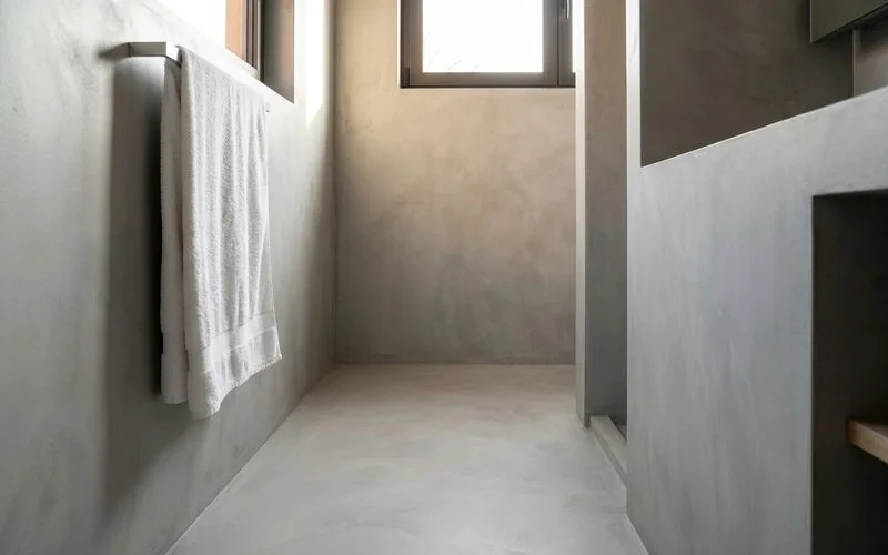Salle de bain renovee avec beton cire gris clair sur sol et murs aspect contemporain et lumineux